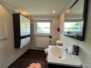 A modern bathroom with a large mirror, a white sink, and a toilet.