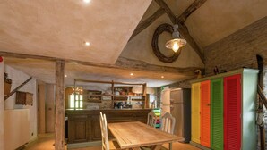 Eine rustikale Küche mit Holzbalken, einem Holztisch und farbenfrohen Schränken.