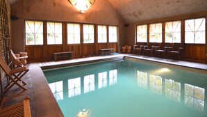 Ein großes Hallenbad mit einer Uhr an der Wand, Holzbänken und großen Fenstern.
