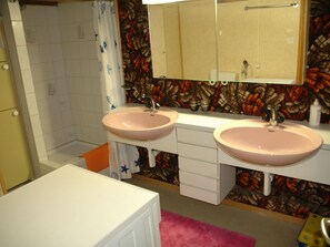 A bathroom with two sinks, a shower, and a mirror.