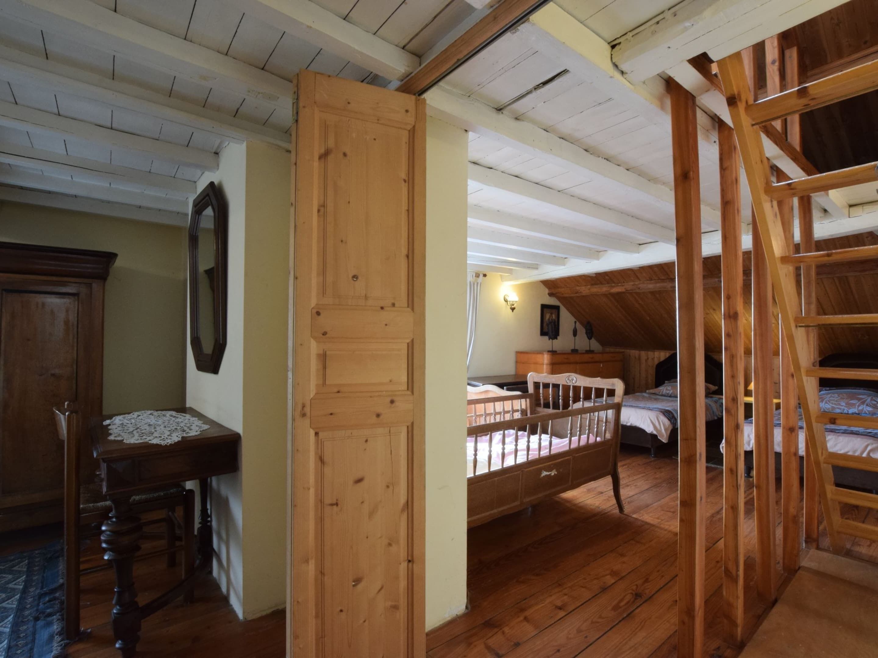 A wooden interior with a loft bed, a desk, and a chair.