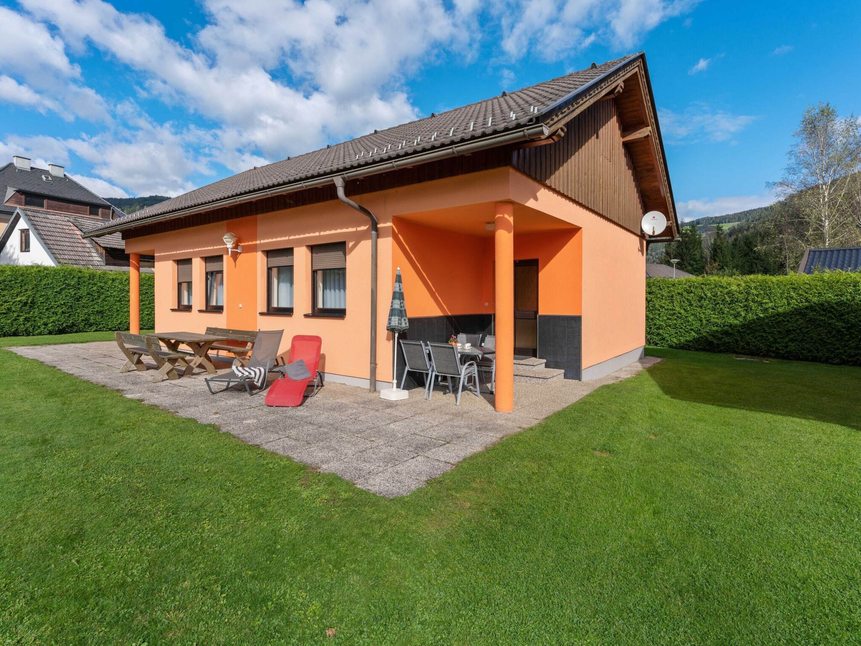 Une maison à deux étages dotée d’un patio couvert, d’une table à manger et de sièges d’extérieur.