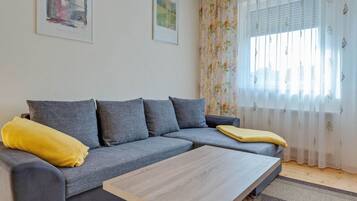 Una sala de estar moderna con un sofá seccional gris, una mesa de centro de madera y cortinas con estampado floral.
