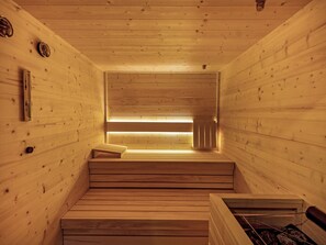 Uma sauna com paredes de madeira, um banco e um aquecedor visível.