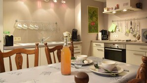 A modern kitchen with a dining table set for two, featuring a coffee maker, a kettle, and various kitchen utensils.