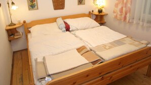 A double bed with a wooden frame, two bedside tables with lamps, and floral wall art. - Lovely Holiday Home near Wernberg (Wernberg)
