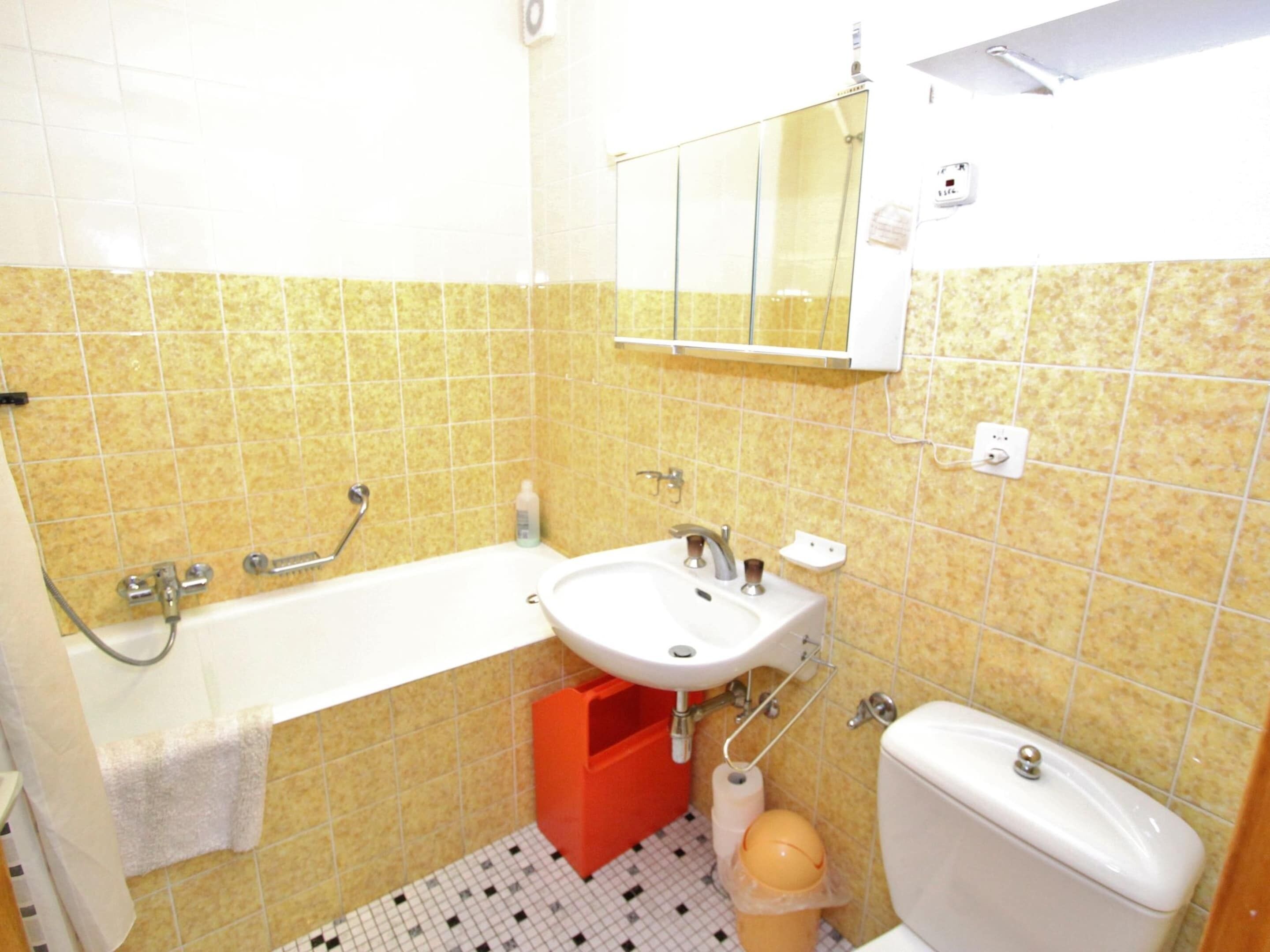 A bathroom with a bathtub, sink, toilet, and a mirror above the sink.