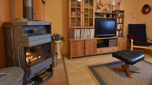 Ein Wohnzimmer mit Kamin, Fernseher, Bücherregal und blauem Sessel.