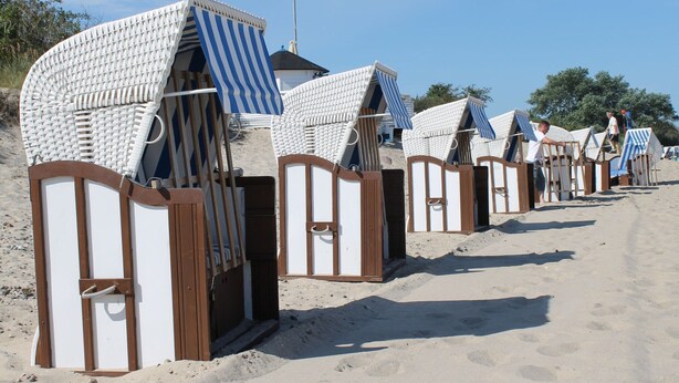 Strandhütten mit gestreiften Markisen, an einer Reihe auf einem Sandstrand platziert.