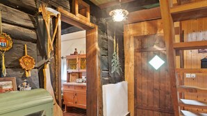 Interior rústico de madeira com porta de madeira, um pequeno armário e um cabideiro.