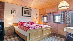 Quarto acolhedor de cabana de madeira com uma cama, mesas de cabeceira, uma mesa e um lustre.