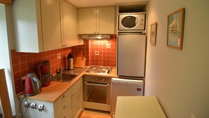 A compact kitchen with a microwave, oven, and coffee maker. - Cozy Cottage in Barvaux-Condroz near Forest (Havelange)