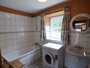 A bathroom with a bathtub, a washing machine, and a sink. - Cozy Cottage in Barvaux-Condroz near Forest (Havelange)