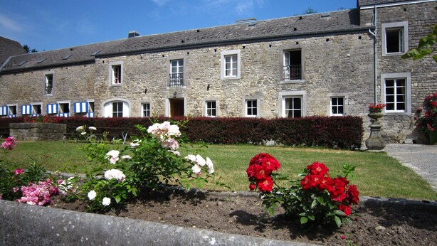A stone building with multiple windows and a well-maintained garden with pink and red flowers. - Cozy Cottage in Barvaux-Condroz near Forest (Havelange)