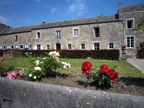A stone building with multiple windows and a well-maintained garden with pink and red flowers. - Cozy Cottage in Barvaux-Condroz near Forest (Havelange)
