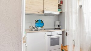 Una kitchenette compacta con un lavabo, una cafetera y un horno pequeño.