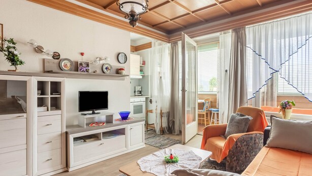 Una sala de estar moderna con televisor, sofá, mesa de centro y un comedor con mesa y sillas.