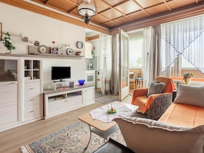A modern living room with a TV, sofa, coffee table, and a dining area with a table and chairs. - Apartment in Carinthia on Lake Woerthersee (Techelsberg am Worther See)