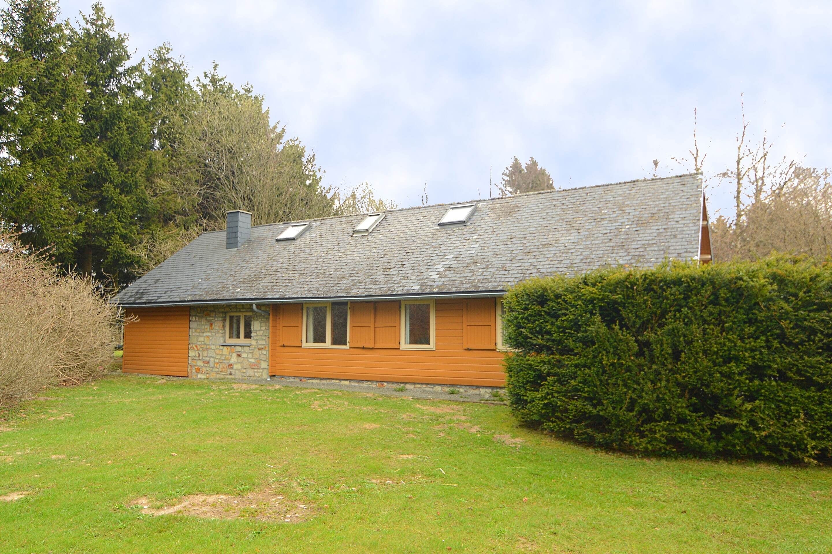 A stone house with a sloped roof, wooden shutters, and a small front porch.