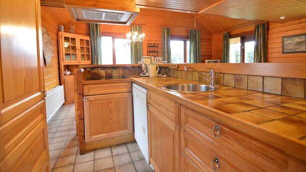 A wooden cabin interior with a kitchen featuring wooden cabinets, a dishwasher, a sink, and a chandelier. - Scenic Chalet in Ovifat (Waimes)