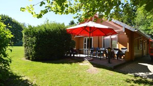 A wooden building with a patio area, outdoor seating, and a red umbrella. - Scenic Chalet in Ovifat (Waimes)