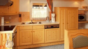 Une cuisine compacte avec des meubles en bois, une cuisinière encastrée, un évier et un four à micro-ondes.