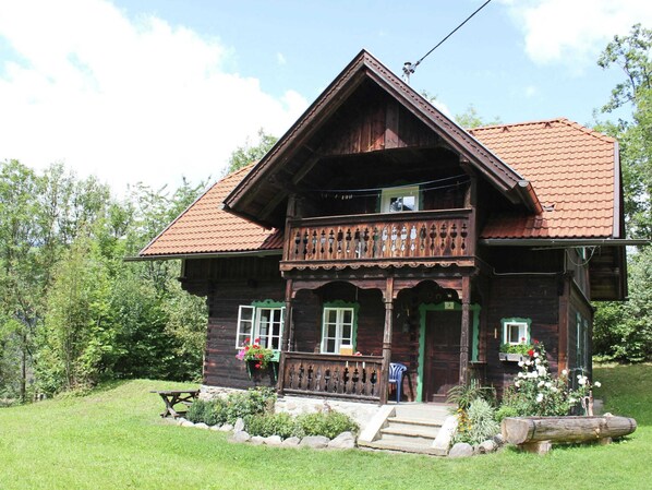 A wooden house with a balcony, a front porch, and a small garden area. - Historic Holiday Home in Gmünd near Cross Country Skiiing (Gmuend in Kaernten)