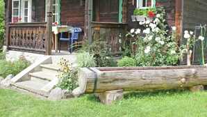 A rustic wooden house with a porch, a small table, and a chair. - Historic Holiday Home in Gmünd near Cross Country Skiiing (Gmuend in Kaernten)