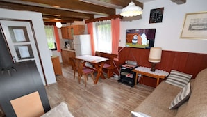 A cozy living room with a sofa, a dining table, and a kitchen area with wooden cabinets and a refrigerator. - Country House in Czech Forest With Pool (Horní Kozolupy)