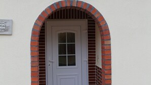 A white door with a glass panel, framed by a brick archway. - Bungalow in Alt Bukow Near the Beach (Alt Bukow)