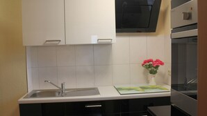 A modern kitchen with black cabinets, a stainless steel sink, and a black range hood. - Bungalow in Alt Bukow Near the Beach (Alt Bukow)