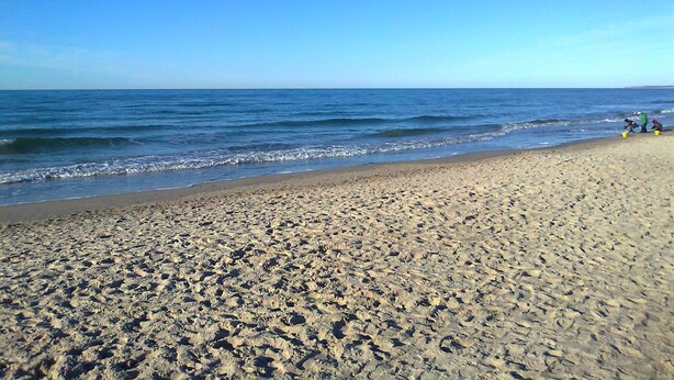 A beach with a clear sky, waves, and footprints in the sand. - Bungalow in Alt Bukow Near the Beach (Alt Bukow)