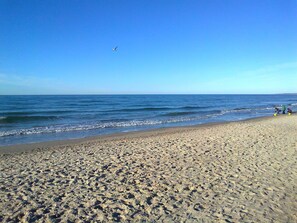 A beach with a clear sky, waves, and footprints in the sand. - Bungalow in Alt Bukow Near the Beach (Alt Bukow)