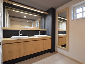 Une salle de bain moderne avec un meuble-lavabo en bois, deux vasques et un grand miroir.