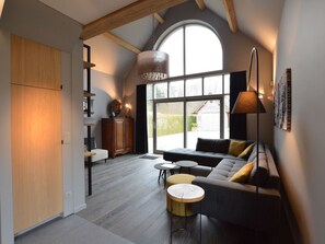 Un salon moderne avec une grande fenêtre, un canapé, une table basse et une lampe.