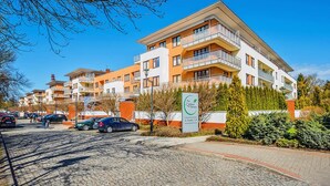 A multi-story residential building with balconies, a parking area, and a sign indicating the name and address. - Apartamenty Sun & Snow Zielone Tarasy (Kolobrzeg)