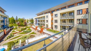 A modern apartment building with multiple balconies, a courtyard with greenery, and a clear blue sky. - Apartamenty Sun & Snow Zielone Tarasy (Kolobrzeg)