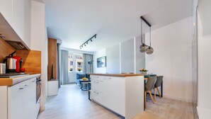 A modern kitchen with a central island, wooden flooring, and pendant lighting. - Apartamenty Sun & Snow Zielone Tarasy (Kolobrzeg)