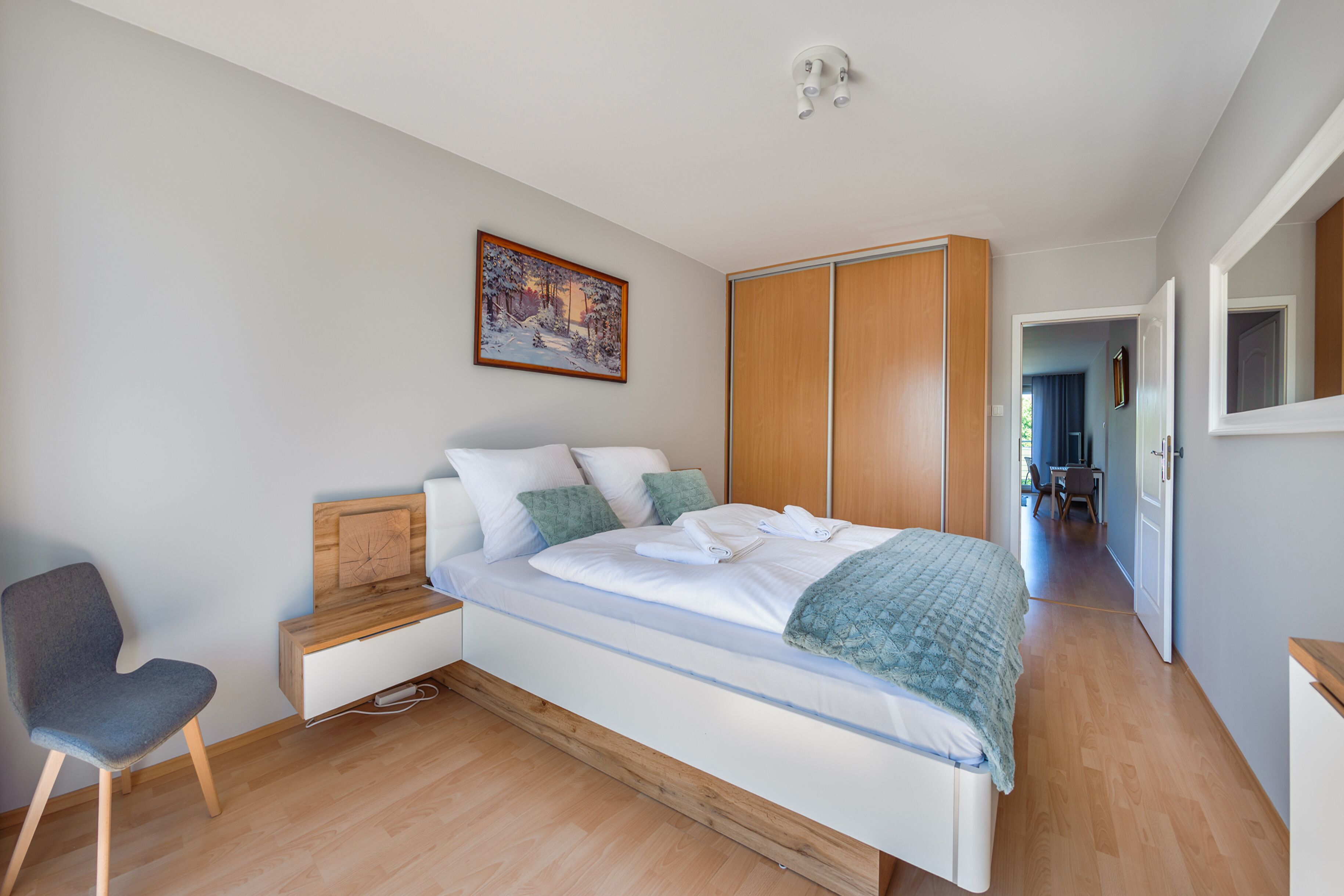 Quarto moderno com cama, cadeira, escrivaninha e guarda-roupa.