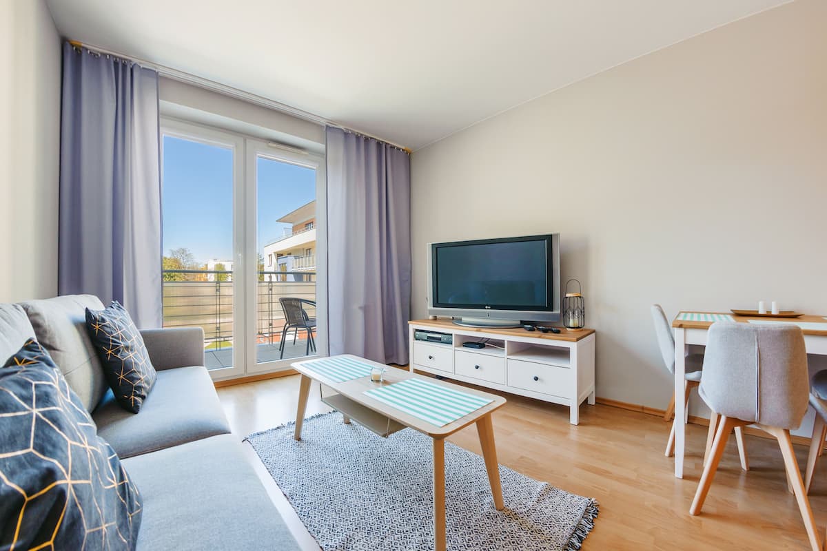 A modern living room with a sofa, TV, dining table, and chairs.