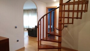 Una escalera espiral de madera en una habitación con piso de madera y paredes blancas.