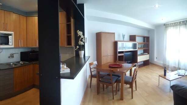 Una cocina moderna con armarios de madera, un microondas y un comedor con mesa y sillas.