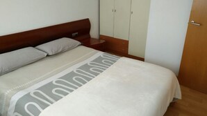 Un dormitorio con cama, cabecera de madera, armario y una puerta.