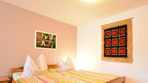 A bedroom with a wooden bed, a colorful striped bedspread, and a wall-mounted quilted tapestry. - Ferienwohnung im Ostseebad Kuhlungsborn (Kuehlungsborn)