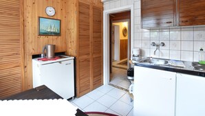 Eine kleine Küche mit Holzvertäfelung, einem Kühlschrank, einer Kaffeemaschine und einem Waschbecken.