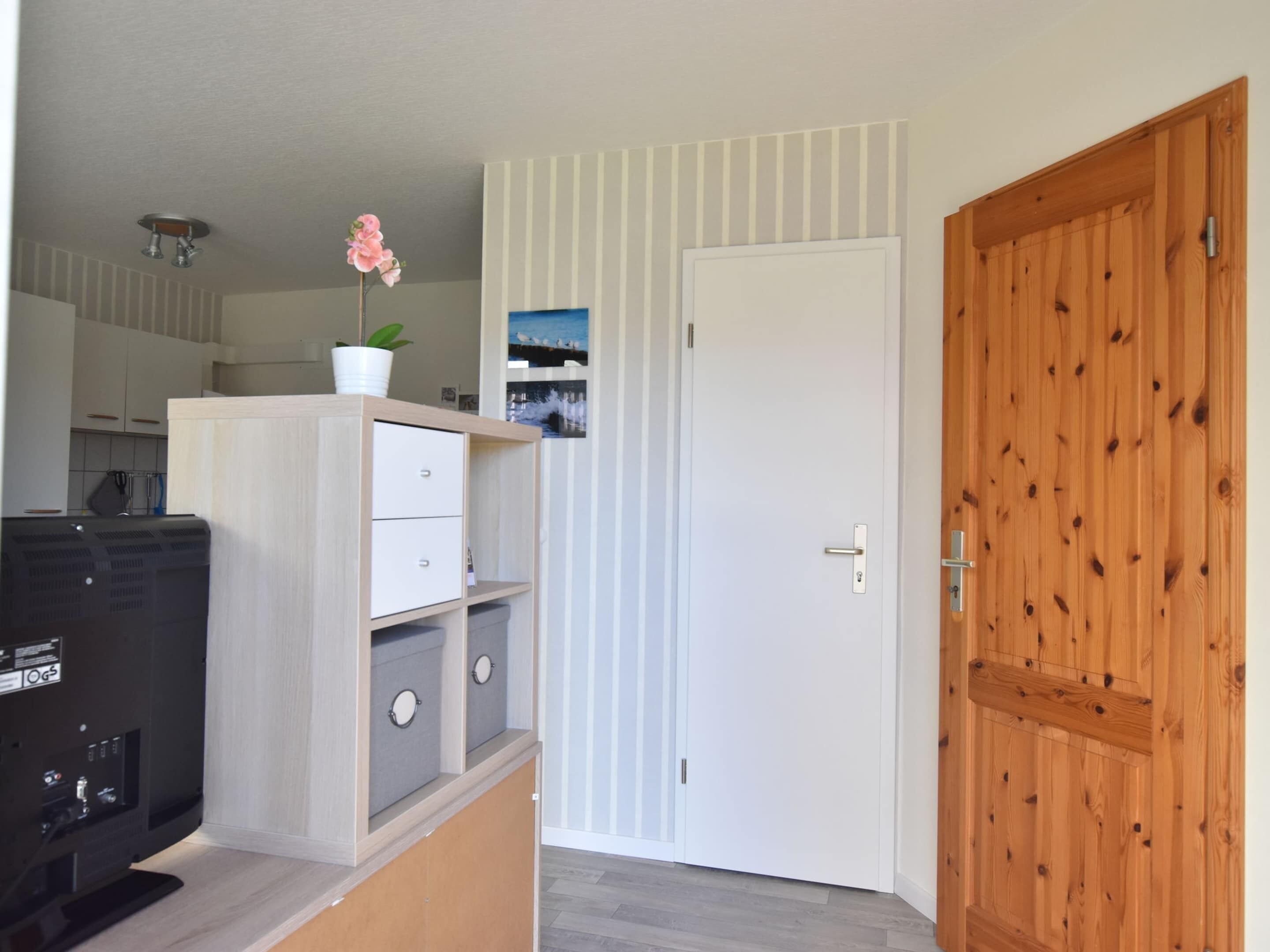 Une pièce avec un meuble en bois, une porte blanche et un mur recouvert de panneaux en bois.