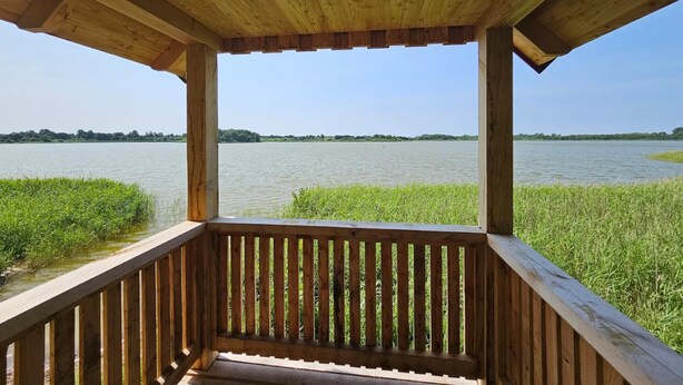 A wooden deck with a view of a calm lake and distant trees. - Fabulous Holiday Home in Thorstorf near Sea (Warnow)