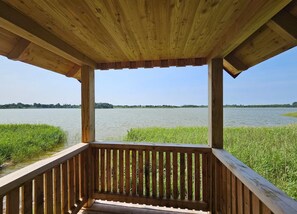 A wooden deck with a view of a calm lake and distant trees. - Fabulous Holiday Home in Thorstorf near Sea (Warnow)