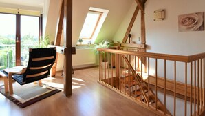 A spacious loft bedroom with a sloped ceiling, wooden beams, a skylight, a wooden staircase, and a view of the outdoors. - Fabulous Holiday Home in Thorstorf near Sea (Warnow)
