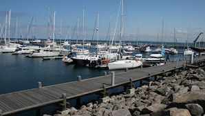 A marina with multiple boats docked, a wooden pier, and rocky shoreline. - Ferienwohnung in Brusow an der Ostseekueste (Kroepelin)